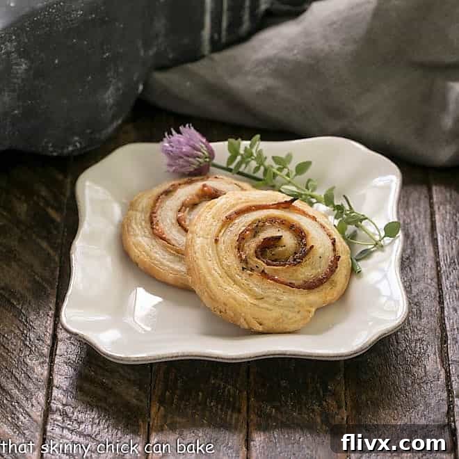 2 pepperoni pinwheels on a square white plate with thyme and chives to garnish
