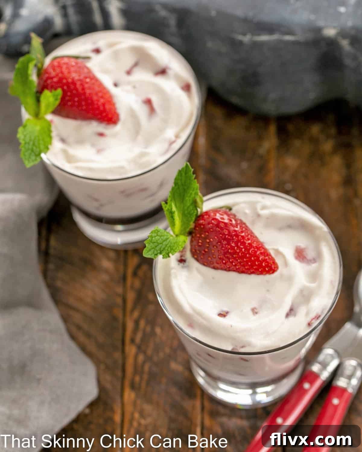 Two glass dishes of No-Bake Strawberry Fool, seen from an overhead perspective, with two red-handled spoons placed beside them, ready for indulgence.