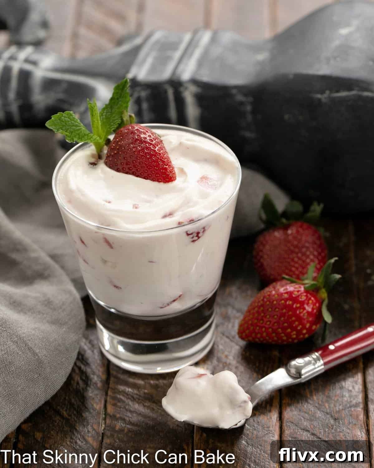 A single serving of No-Bake Strawberry Fool in a glass dish, with a spoon having removed a bite, showcasing the creamy, berried texture.
