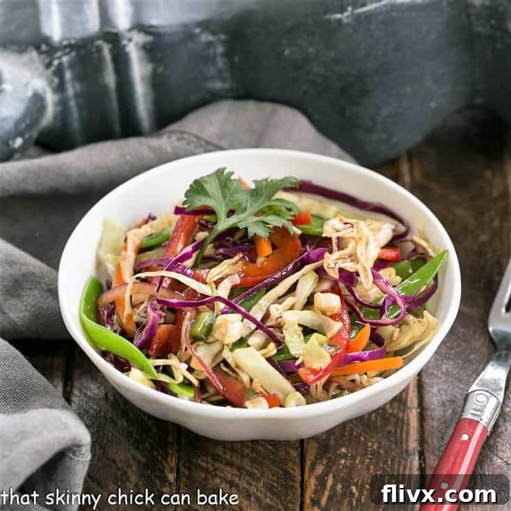 A small white bowl of Asian salad with a red handle fork