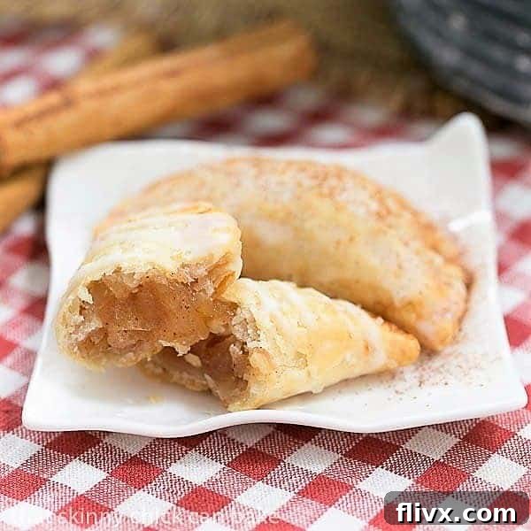 Two Fried Apple Pies resting on a rustic ceramic plate, with one expertly broken open to reveal its luscious, cinnamon-spiced apple filling, inviting you to take a bite.