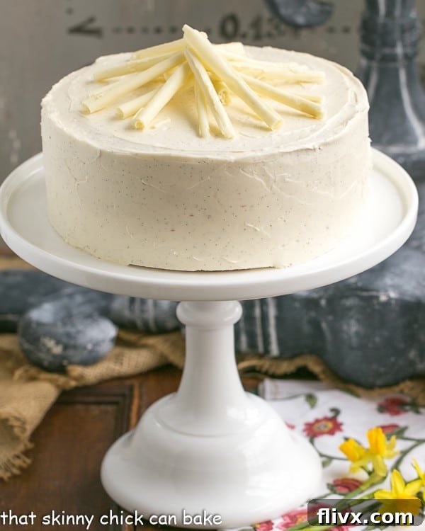 White Birthday Cake topped with white chocolate curls on a cake stand
