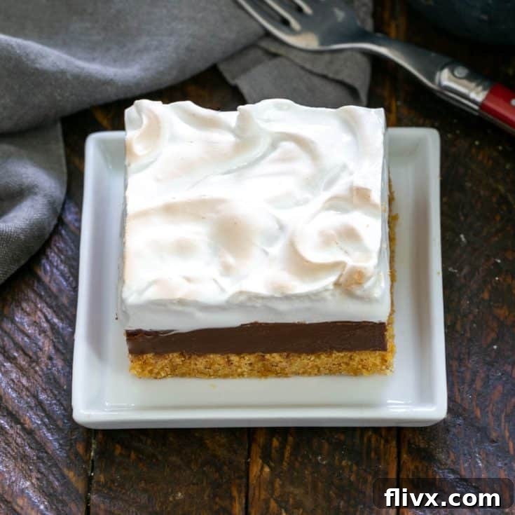 One S'mores Fudge Bar prominently displayed on a square white plate, with the beautifully toasted homemade marshmallow topping standing tall and inviting.