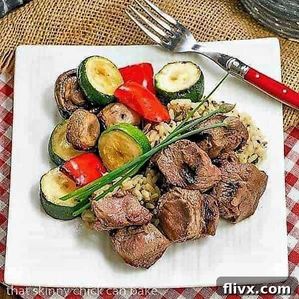 Grilled Teriyaki Beef Kabobs presented beautifully on a square white plate with a side of rice.