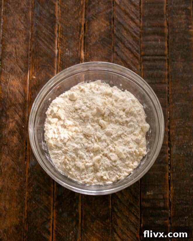 Mixing flour, powdered sugar, salt, and cold butter pieces to form the shortbread crust mixture.