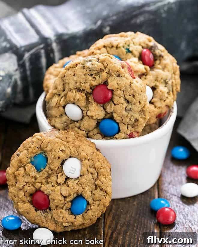 Close-up of Peanut Butter Oatmeal Cookies with M&Ms in a small white bowl, surrounded by loose patriotic M&Ms