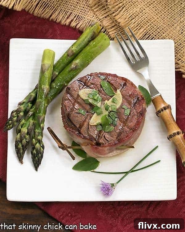 Overhead view of a perfectly grilled beef tenderloin steak adorned with melted garlic herb butter, presented on a minimalist square white plate.