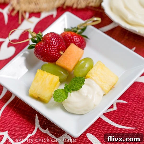 Fruit Kebabs with White Chocolate Mascarpone Dip on a small square plate with a dollop of dip and a sprig of mint for garnish.