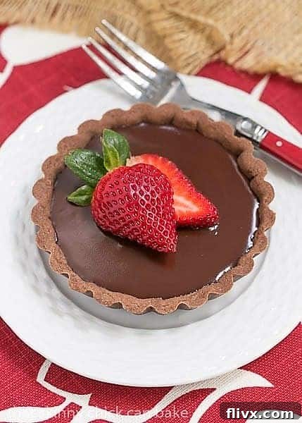 A Double Chocolate Tartlets on a white dessert plate with a red handled fork
