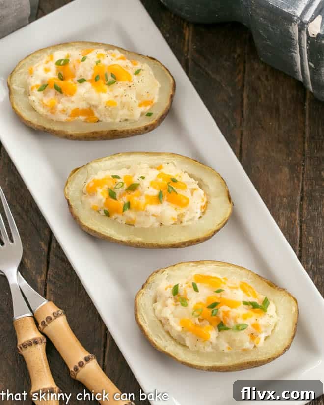 3 twice baked potatos on a white platter with 2 bamboo handled forks.