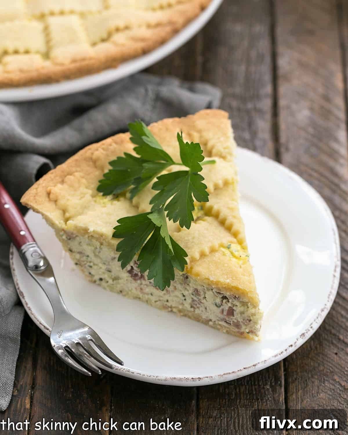 A perfectly sliced piece of Pizza Rustica, revealing its rich, layered filling of cheeses and prosciutto, served on a pristine white plate and garnished with a fresh sprig of parsley.