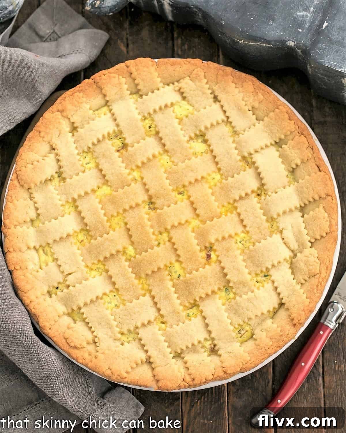 An inviting overhead view of a freshly baked Pizza Rustica, with a red-handled knife poised nearby, showcasing its golden crust and the artistry of the lattice top.