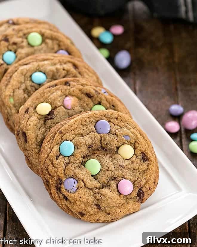 Delightful brown butter cookies generously speckled with vibrant pastel-colored Easter M&M's, arranged on a rustic wooden surface.