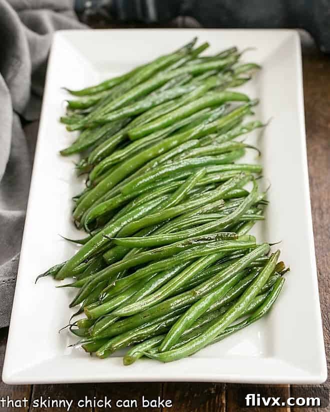 Vibrant Asian Green Beans artfully arranged on a pristine white ceramic platter, showcasing their appealing texture and rich color.