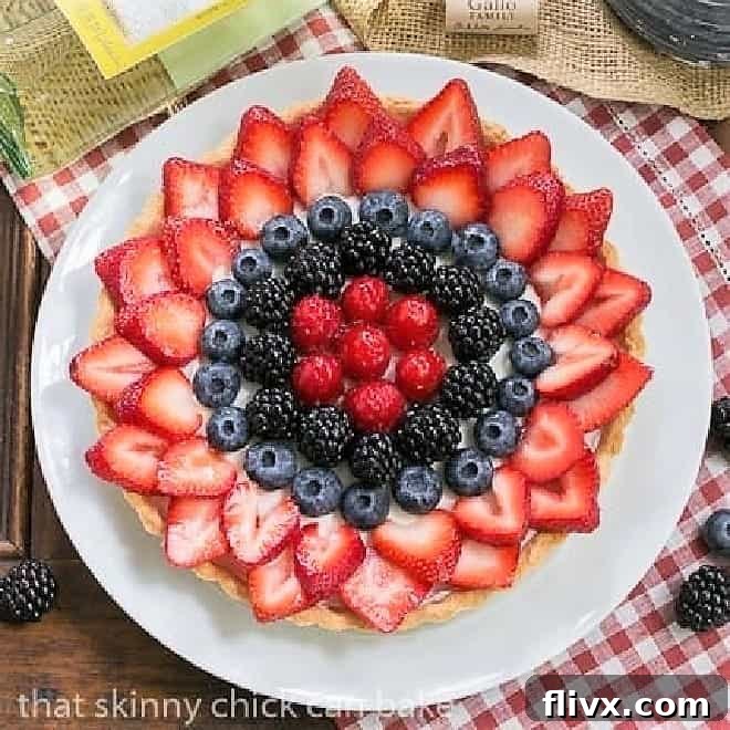 Beautiful Summer Fruit Tart on a white plate, accompanied by a bottle of chilled white wine, setting the scene for an elegant summer gathering.