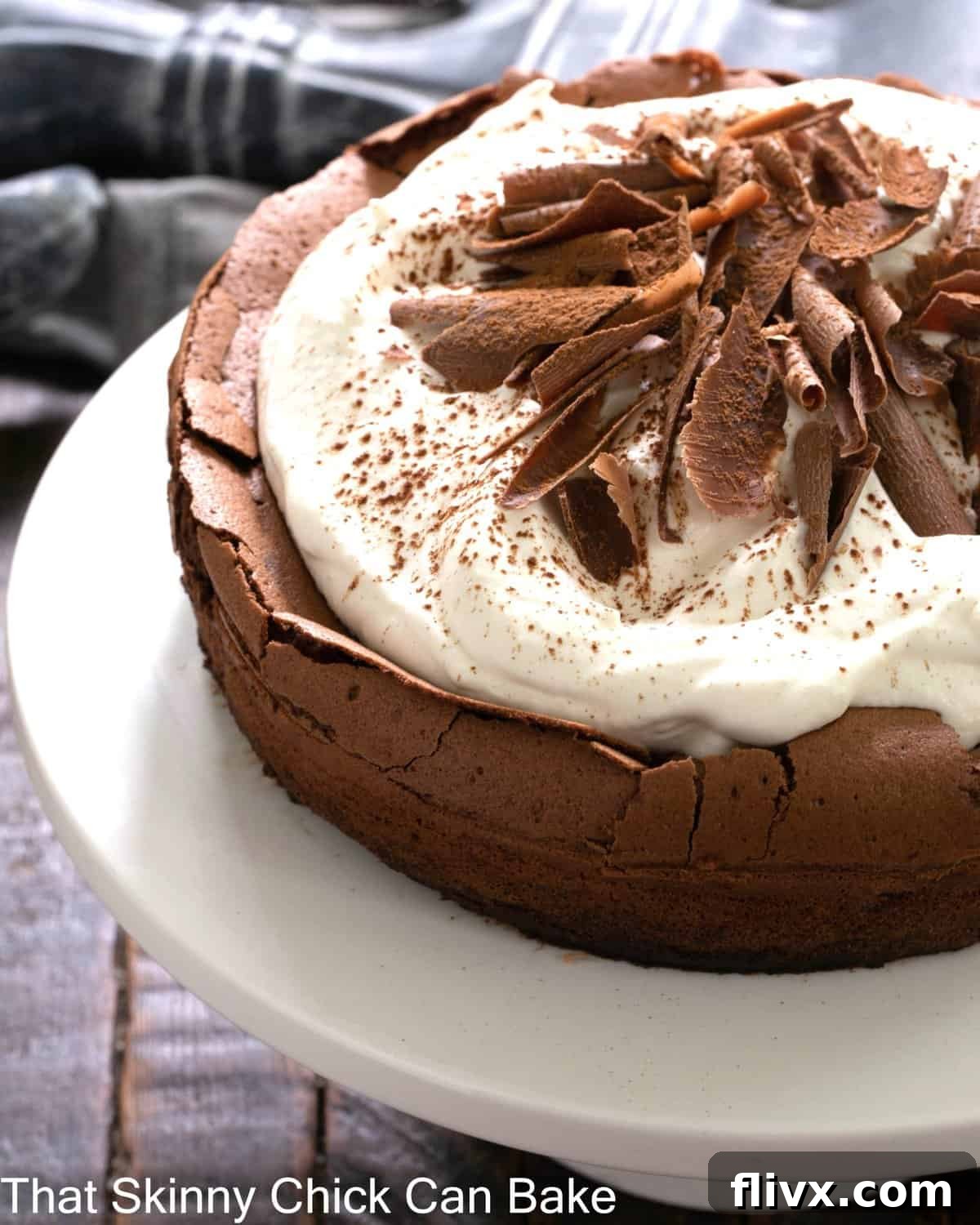 Left side of a Chocolate souffle cake on a white cake stand.