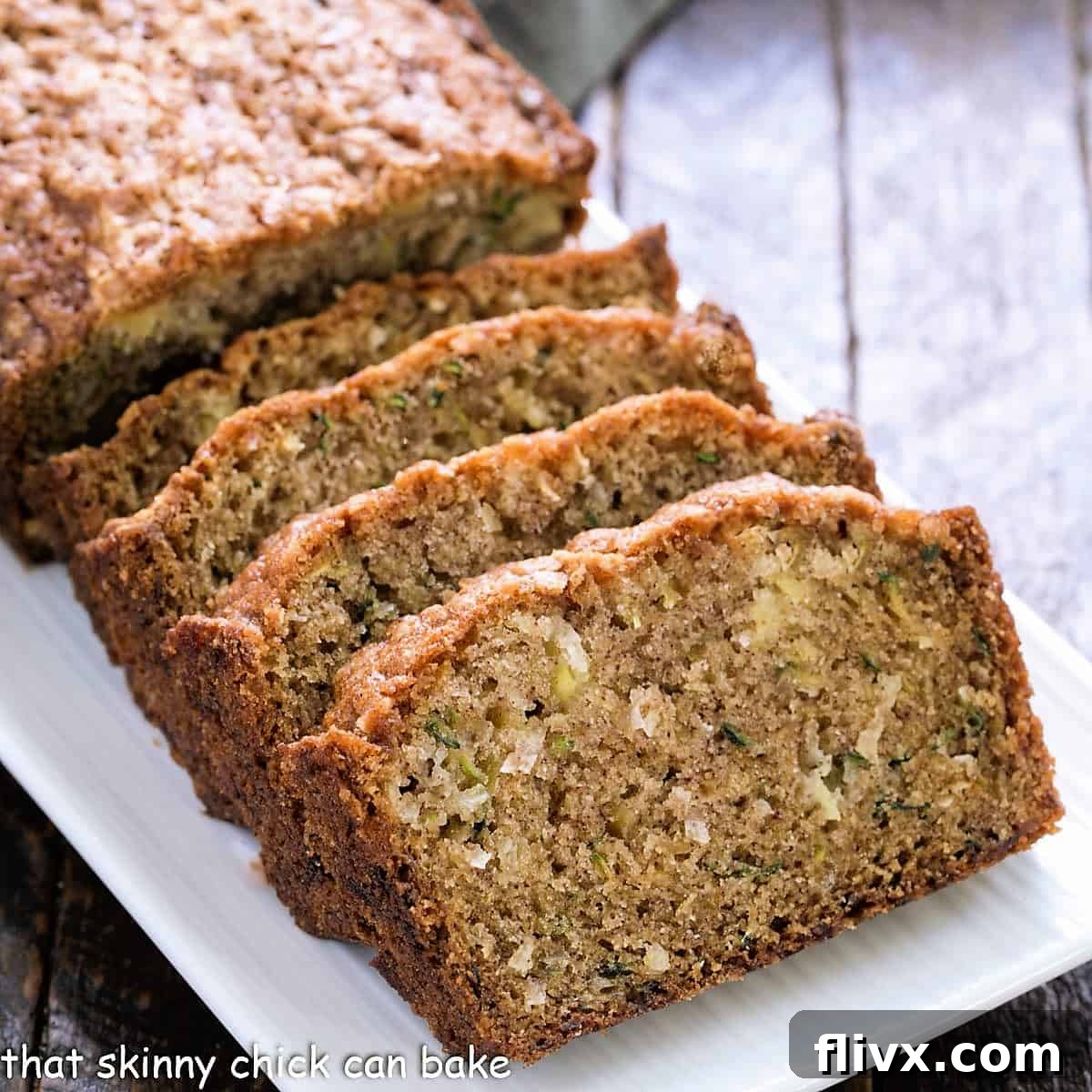 Two slices of moist Pineapple Coconut Zucchini Bread on a white plate, highlighting the delicious texture and tropical inclusions like pineapple, coconut, and walnuts.