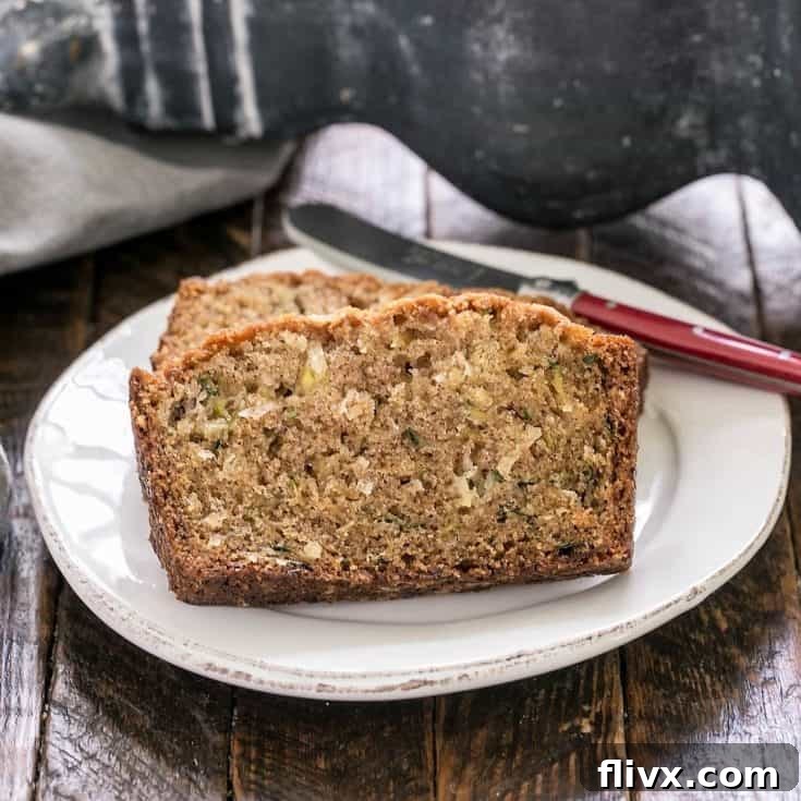 Sliced zucchini bread recipe on a white plate with a red handled knife
