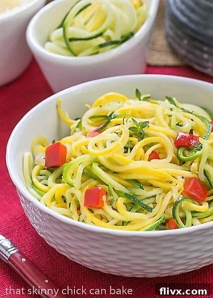 Close-up of Zucchini Noodles with Parmesan in a white basket weave bowl, ready to be enjoyed with a red-handled fork.