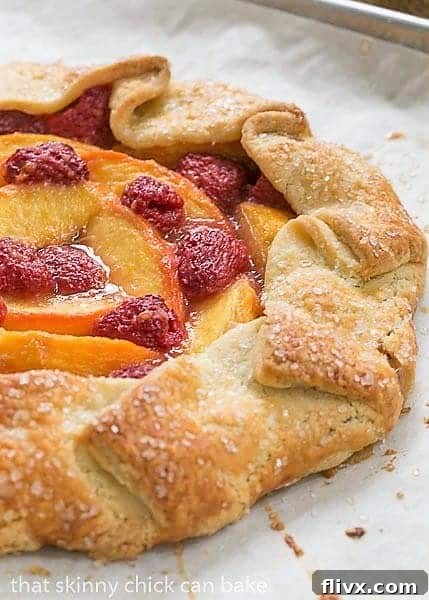 Close-up view of a Peach Raspberry Galette on a parchment-lined baking sheet, ready to go into the oven.