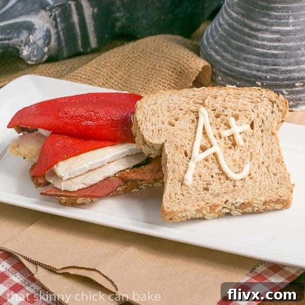 A gourmet Roast Chicken, Brie, and Bacon Sandwich beautifully arranged on a white tray, showcasing its delicious layers.