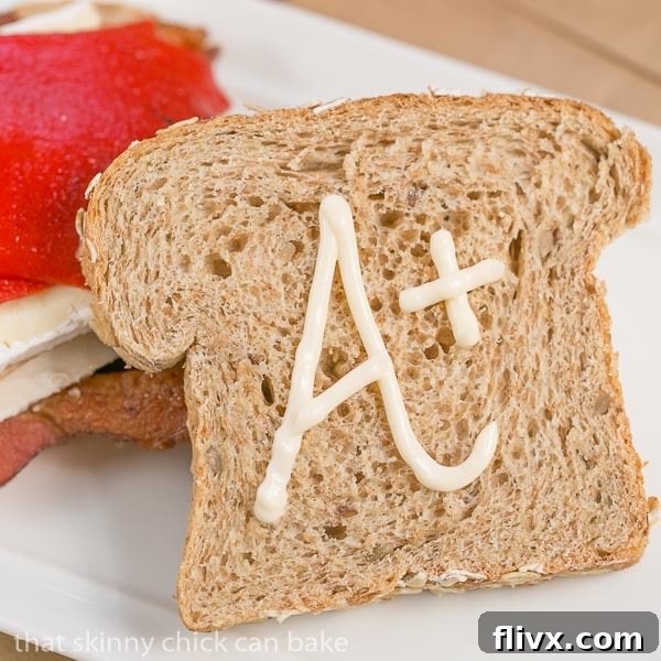 A close-up of a Roasted Chicken, Brie, and Bacon Sandwich with the top slice of bread slightly ajar, revealing the rich fillings.