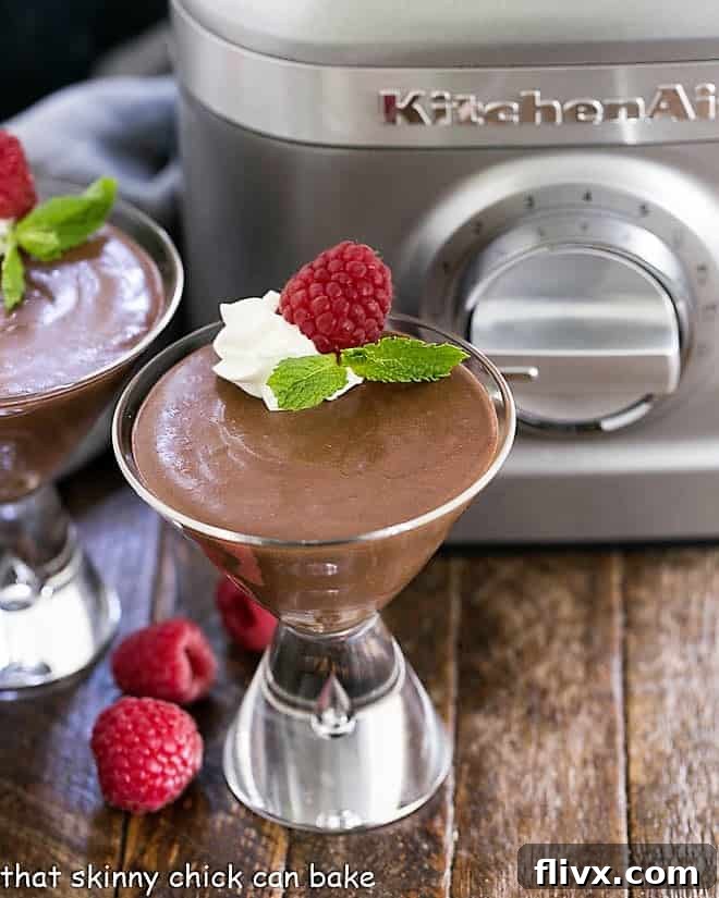 A single serving of Blender Chocolate Mousse, beautifully presented in a martini glass, topped with a generous swirl of whipped cream and garnished with fresh, vibrant raspberries, ready to be savored.