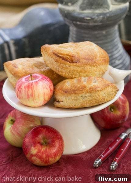 Beautifully baked Chaussons aux Pommes displayed on a ceramic tray, with fresh apples in the background, ready to be enjoyed.