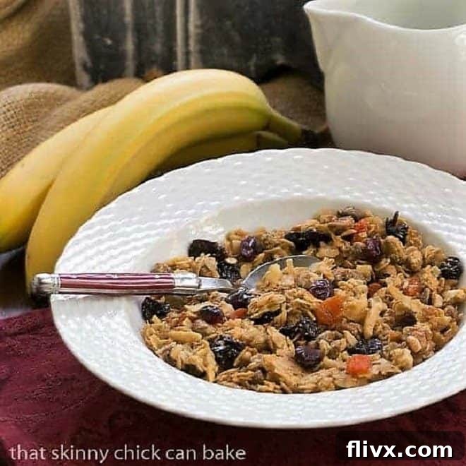 Pistachio Coconut Granola in a white cereal bowl with a red handled spoon, ready to be eaten.