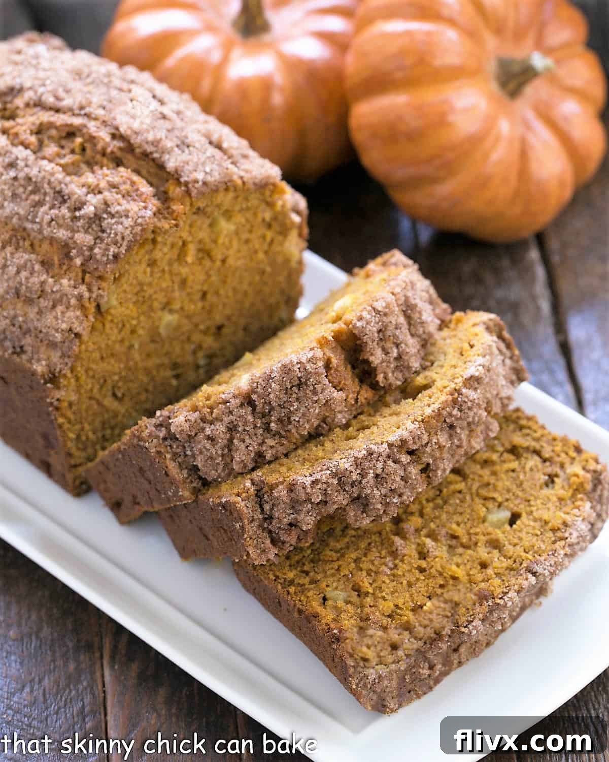 Pumpkin Bread with Apples sliced on a white ceramic tray with 2 mini pumpkins.