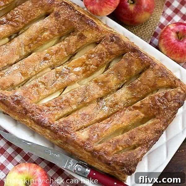 An inviting overhead view of a golden Maple Glazed Apple Tart resting on a charming red and white checkered napkin, highlighting its rustic elegance.