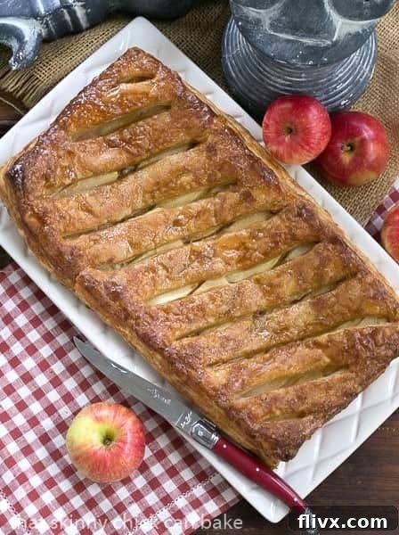 A beautifully presented Maple Glazed Apple Tart, whole and golden brown, sits on a rustic white serving tray, ready to be enjoyed.