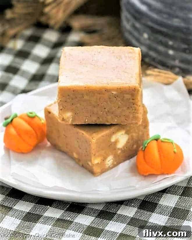 A festive stack of Easy Pumpkin Fudge squares on a white plate, adorned with small candy pumpkins, ready for a fall celebration.