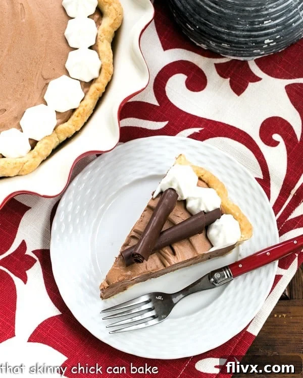 Classic French Silk Pie - A sublime, dreamy chocolate creation Overhead view of a slice of French Silk Pie on a white plate with a red handled fork.