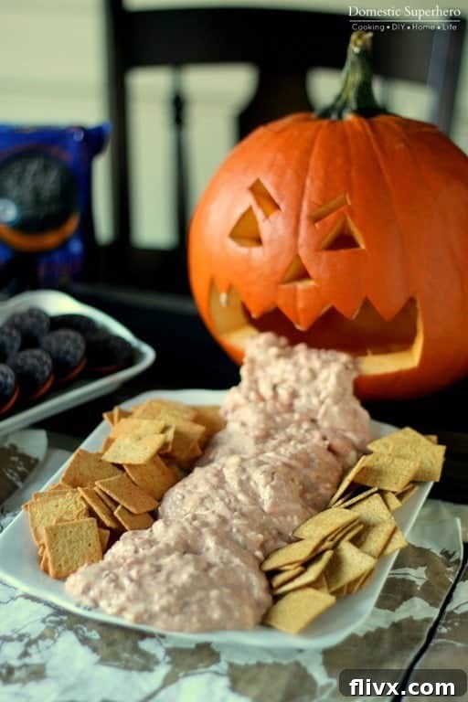 Halloween Chunky Cheese Dip served from a carved pumpkin 'vomiting'