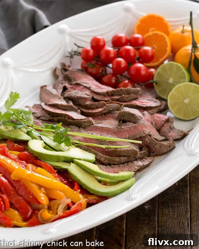 A vibrant platter of Grilled Flank Steak Fajitas, with thinly sliced steak, colorful bell peppers and onions, and an assortment of fresh toppings like avocado, cilantro, and limes, ready to be assembled into tortillas.