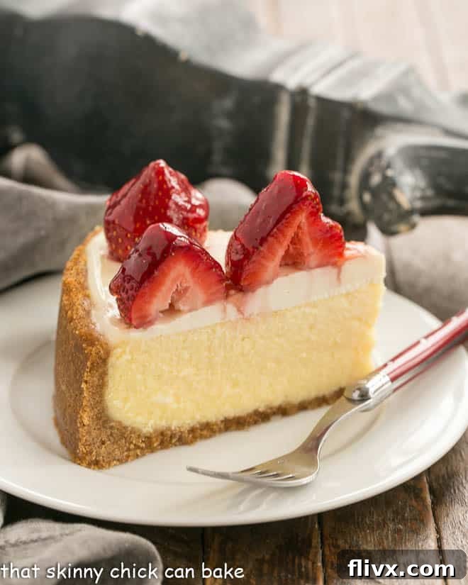 Strawberry Topped Cheesecake Slice on a white plate with a red handled fork.