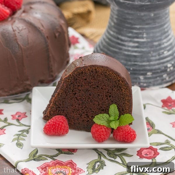 A perfectly sliced piece of Chocolate Buttermilk Bundt Cake on a square white dessert plate, showing its moist, dark crumb.