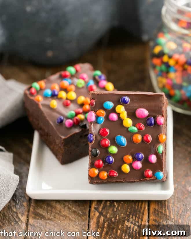 Two cosmic brownies on a small square ceramic plate, garnished with colorful sprinkles.