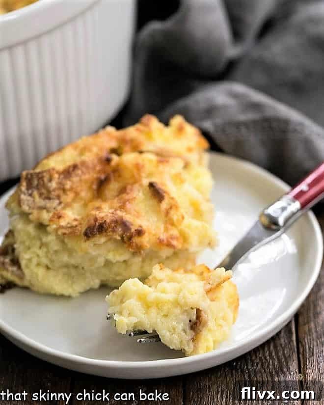 A close-up of a bite of cheese soufflé on a red-handled fork, showing its fluffy texture.