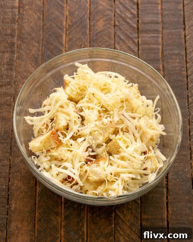 Add milk, grated cheese, salt, and pepper to the buttered bread cubes.