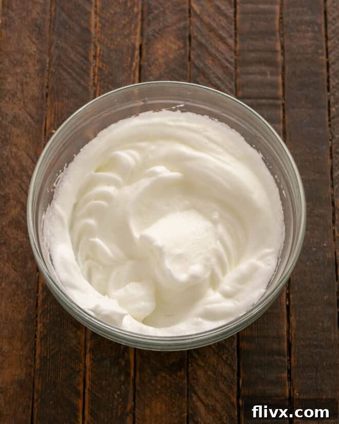 Whip egg whites until stiff peaks form, ensuring they are light and airy.