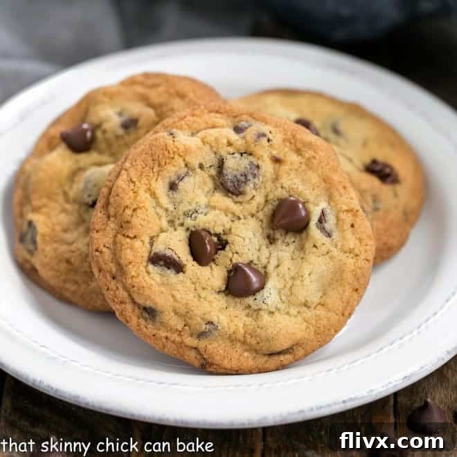 Thin and Chewy Chocolate Chip Cookies on a round white plate, perfectly baked with melted chocolate chips visible.
