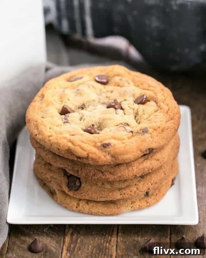 A stack of golden-brown Thin Chewy Chocolate Chip Cookies on a square plate, showcasing their delicate texture and melted chocolate.