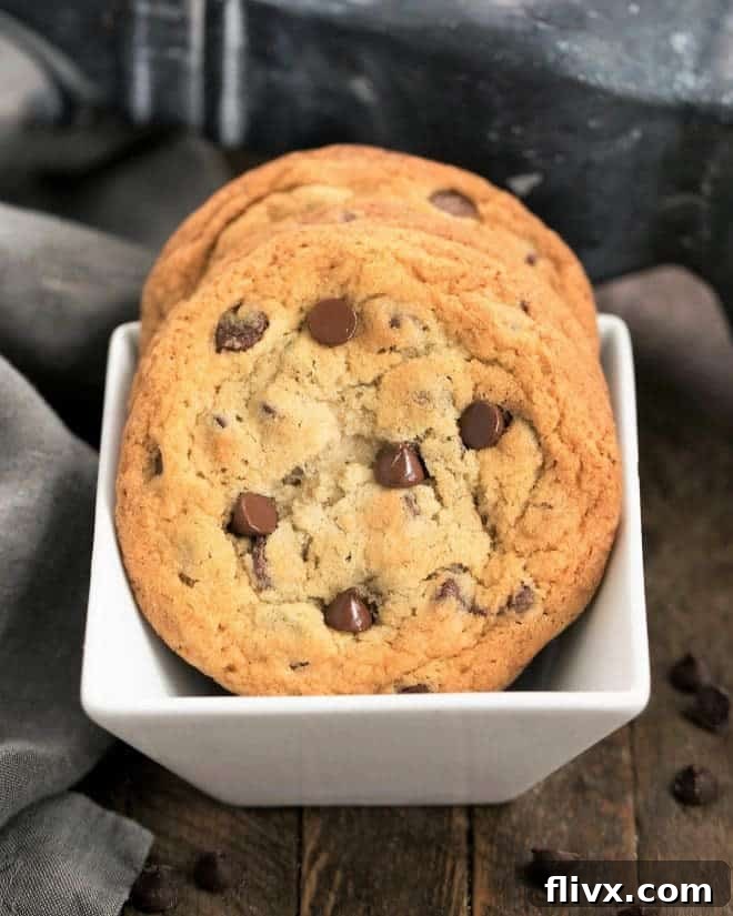 Thin Chewy Chocolate Chip Cookies arranged in a square white bowl, ready to be enjoyed.