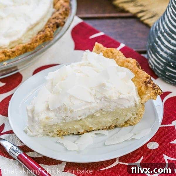 A beautifully sliced Coconut Cream Pie, showing layers of coconut crust, creamy custard, and whipped cream topping. Perfect for any celebration.