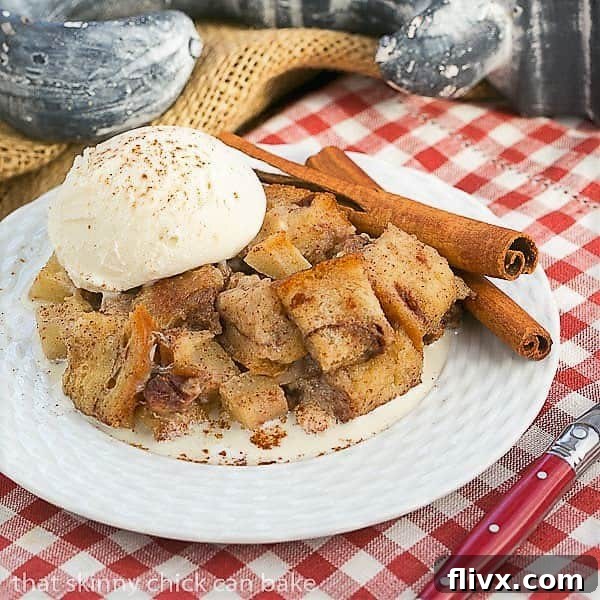 Slow Cooker Apple Pecan Bread Pudding side view on a white plate over a checked napkin, garnished beautifully with a dusting of cinnamon