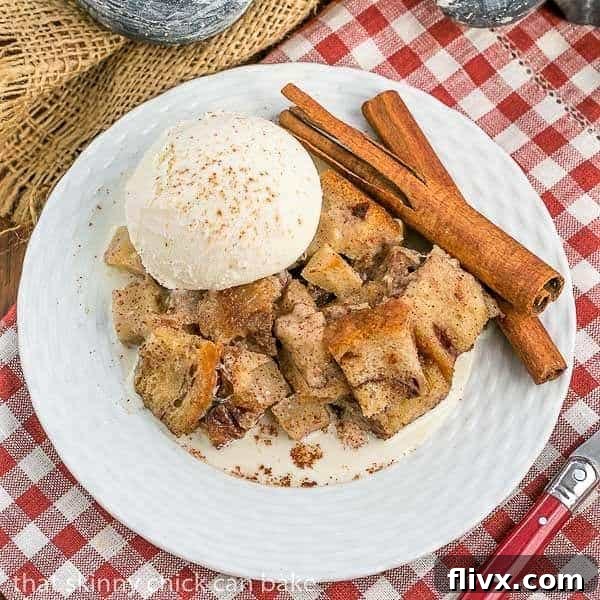Slow Cooker Apple Pecan Bread Pudding on a round white plate on a red/white checked napkin, ready to be enjoyed with its golden crust