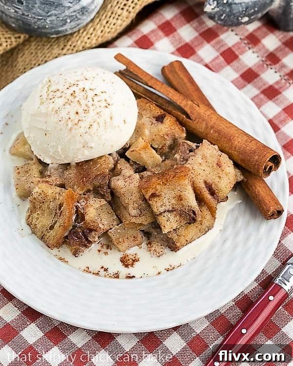 Slow Cooker Apple Pecan Bread Pudding overhead view on a white plate with a scoop of vanilla ice cream and cinnamon sticks, beautifully presented and ready to eat