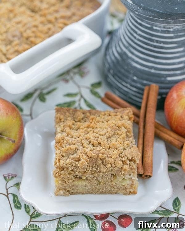 Apple Coffee Cake slice on a square white plate with cinnamon sticks